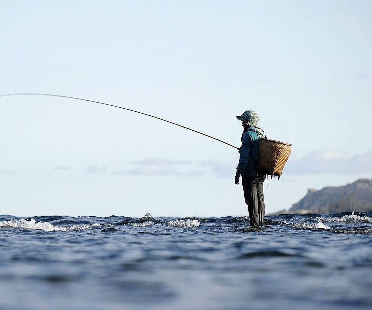 Angler casting from the river bank at dawn